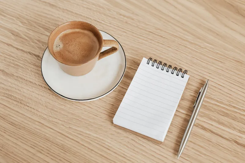 Wooden table with coffee and notebook