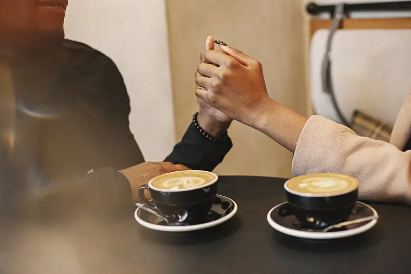 Couple holding hands next to coffee cups