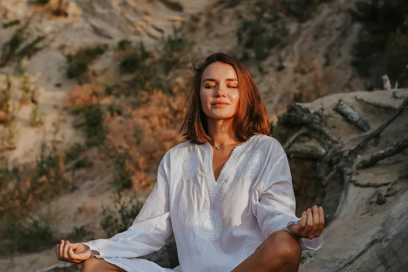 Woman meditating on tree log at dawn
